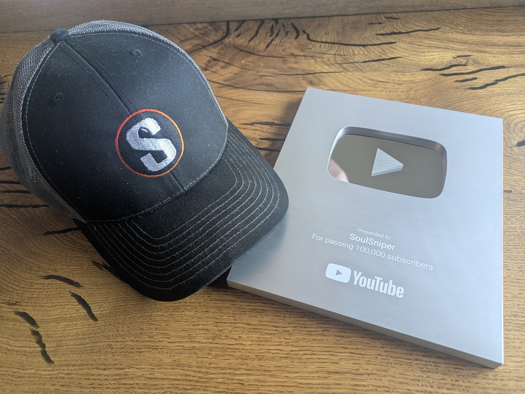 SoulSniper's silver play button plaque and branded hat